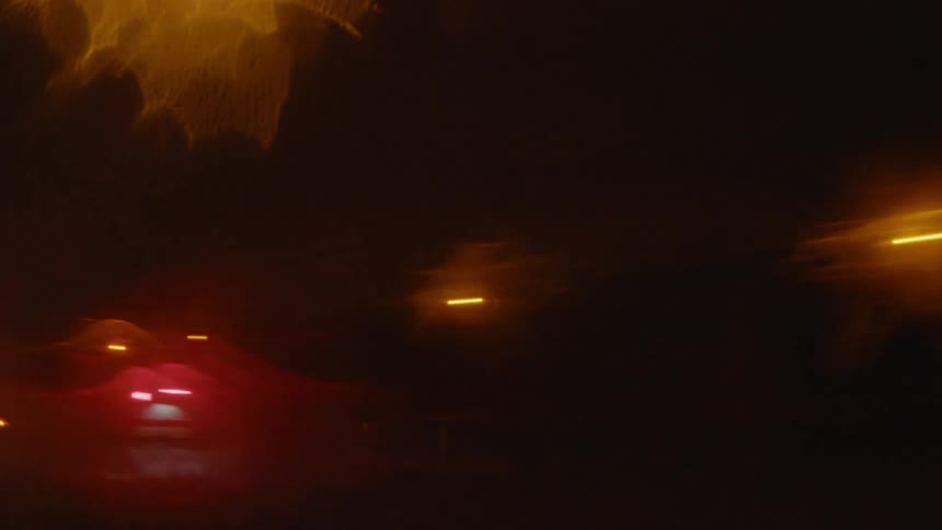 A semi truck traveling beneath a glowing street lamp at night