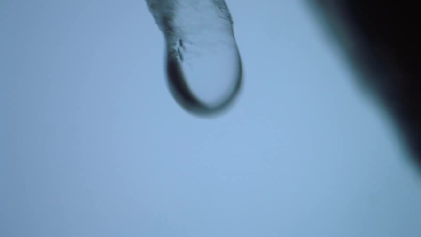 A drop of water falls from a melting icicle