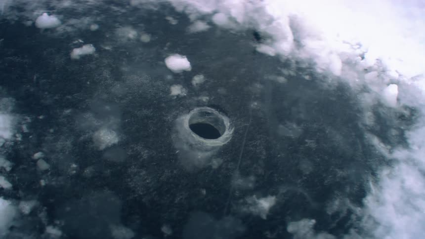 A small hole on the frozen surface of a lake at winter
