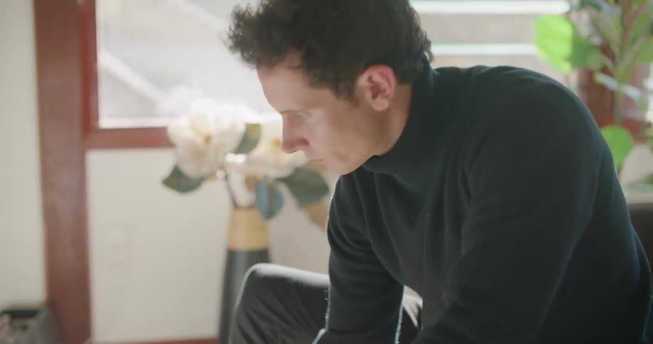 A man sits on his couch at home and uses his laptop