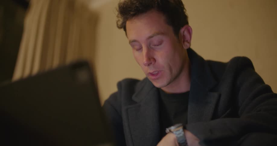 A man is drinking coffee and talking on a laptop