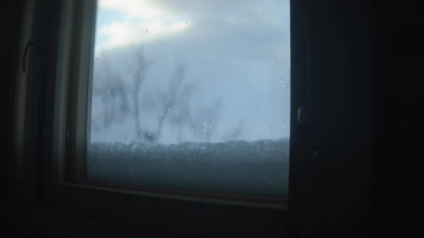 Snow sitting on a windowsill on a cloudy winter day