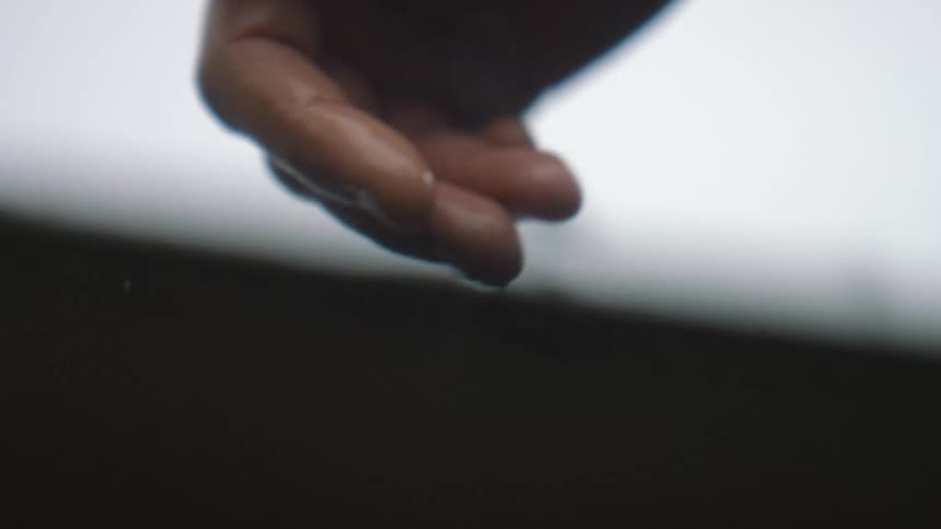Person moves hand in and out of water on overcast day