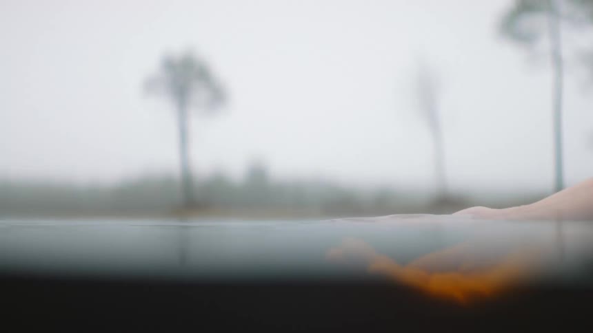 Person submerges hand in water before raising it and letting water drops flow between fingers