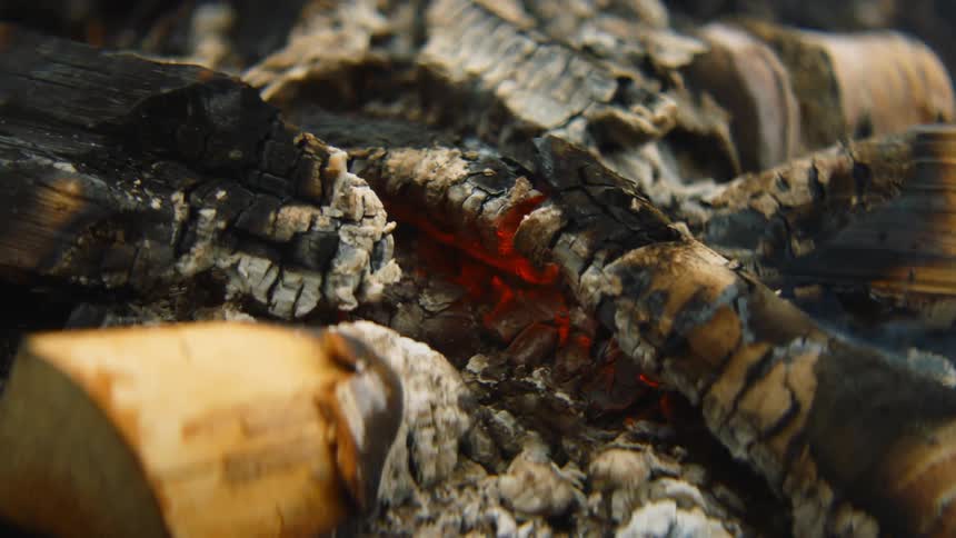 Smoking embers burning in what is left of a campfire