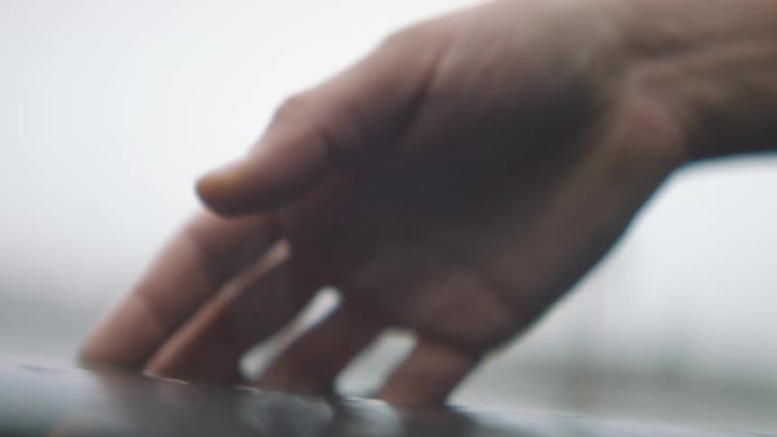 A hand waving over the surface of a calm reservoir
