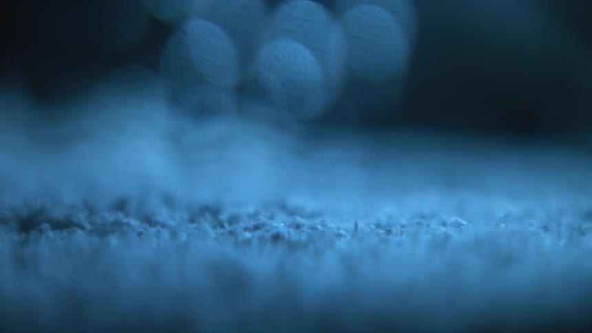 A layer of blue powder bounces and tumbles atop a vibrating surface