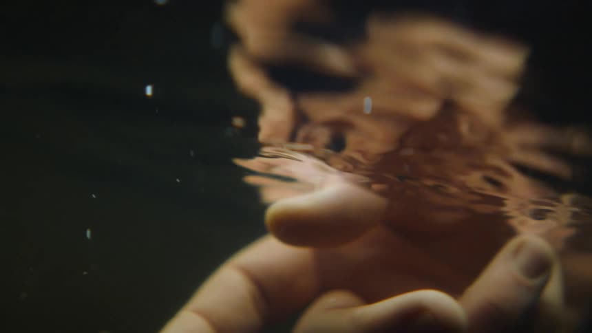 A person moving their hand through rippling water