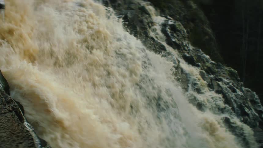 A river with a waterfall and rocks with trees the sky and clouds in the background