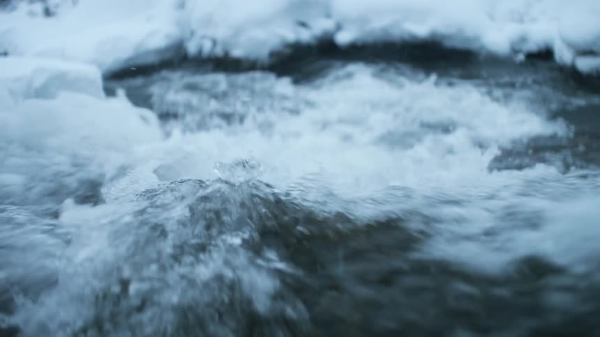 River water flows and splashes with snow on the banks
