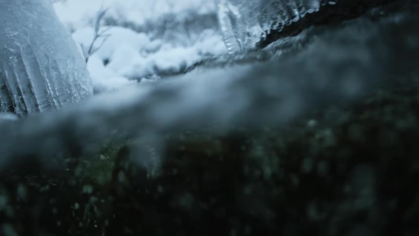 Water in the river flows between blocks of ice and past the snowy river bank