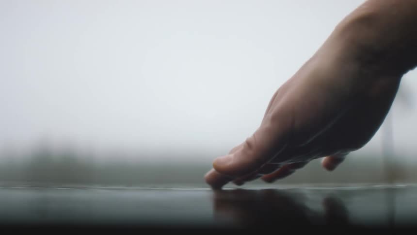 A person runs their fingers through running water outdoors during the day