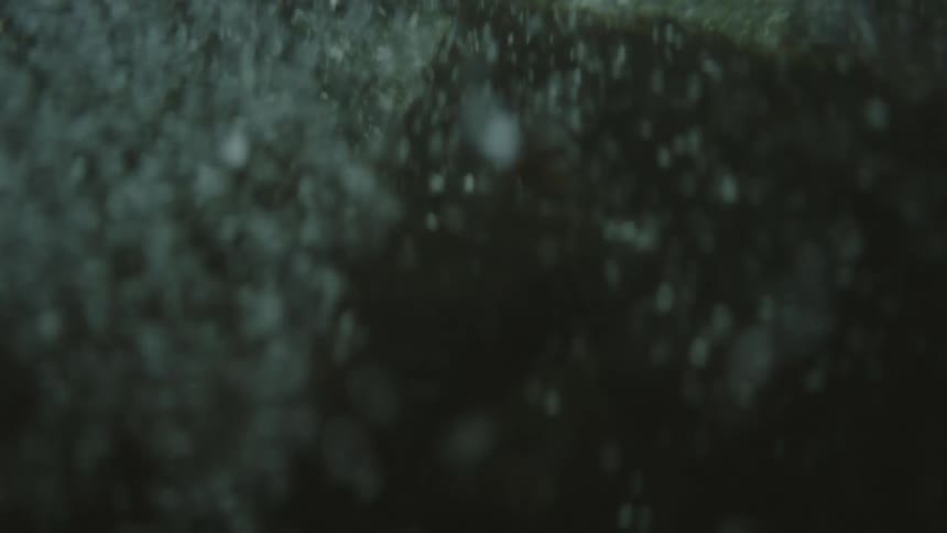 Water flows and churns forming bubbles against grayish background