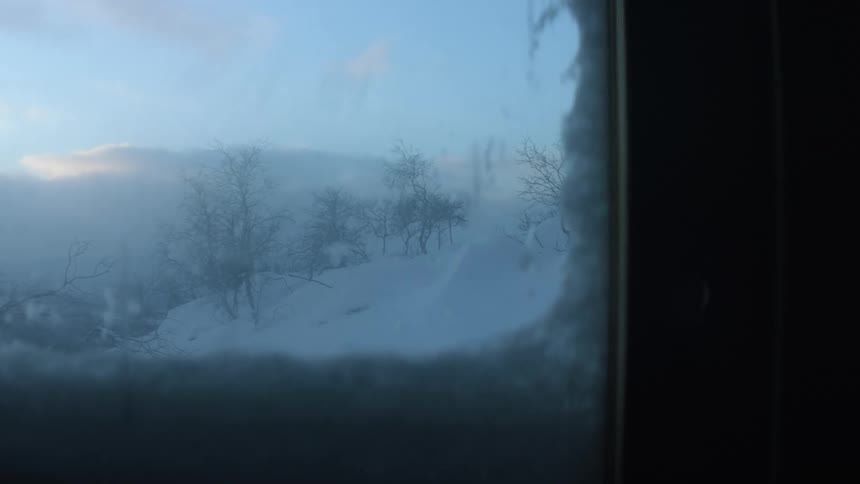 A room with flashing lights with a window with snow trees the sky and clouds in the background