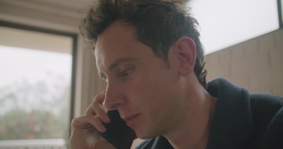 Man sitting on a room talking on a smartphone