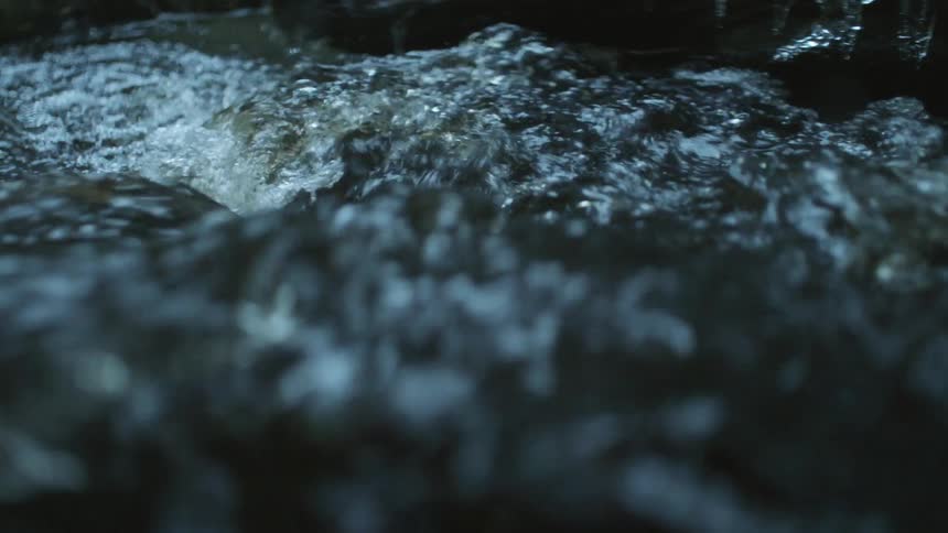 River water flows rapidly past banks creating foam as water churns