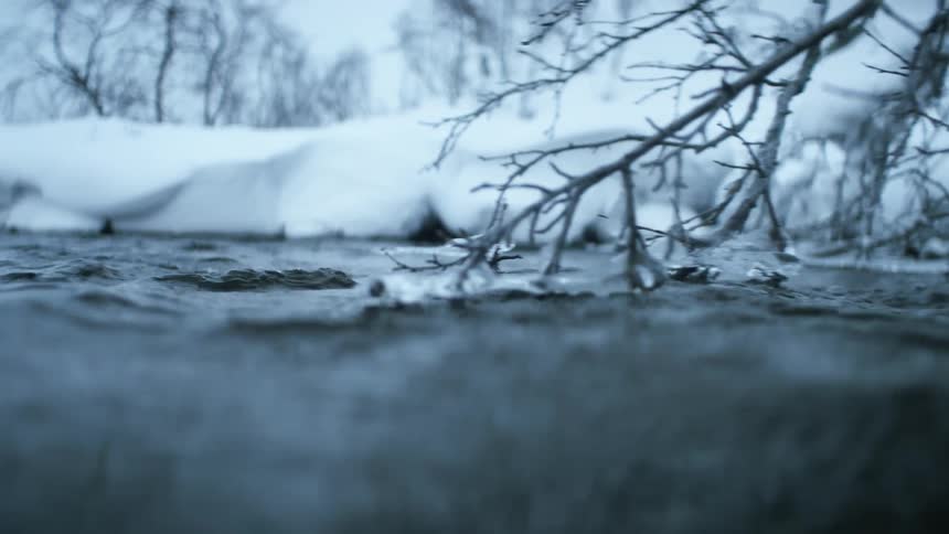 River water rushes past snow covered banks