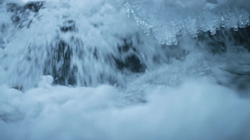 A river with rocks and icicles with the sky and clouds in the background
