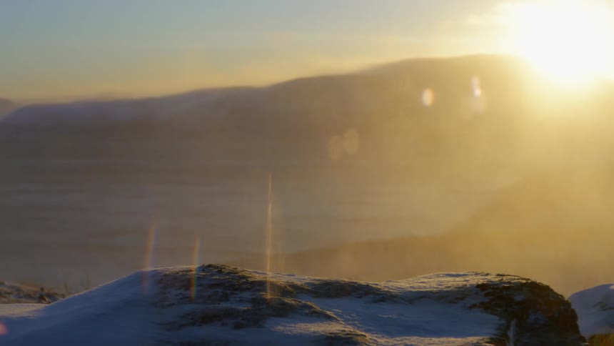 Snow blows over the mountains on a sunny day