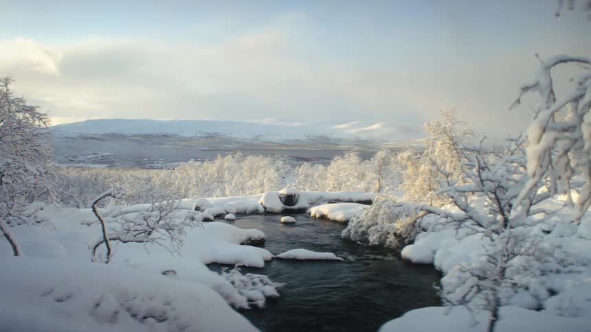 Creek flowing in the snow covered countryside at morning