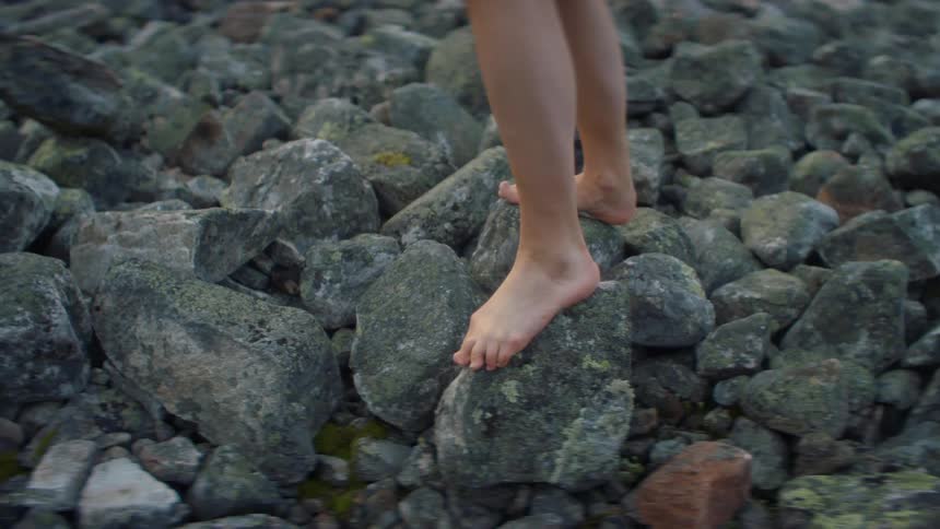 A person walking barefoot outdoors on large rocks