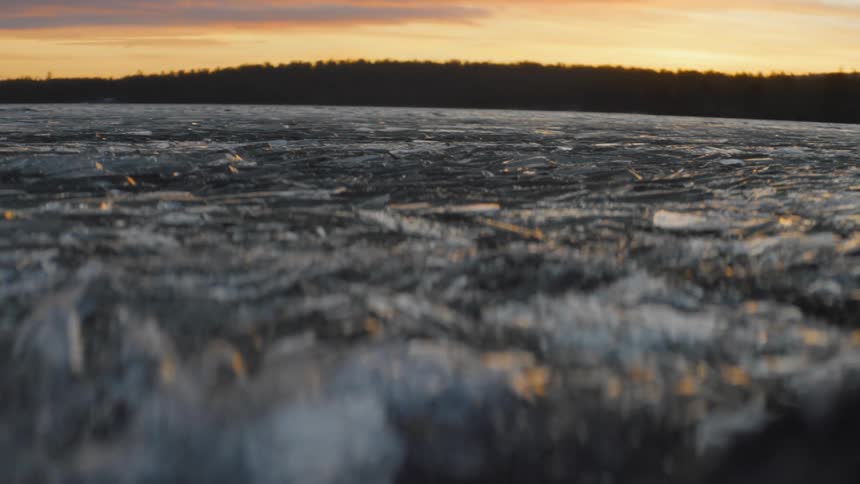 Ice on the frozen surface of a river near the hills at sunset