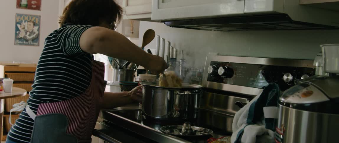 A woman stirs pasta in a pot at home