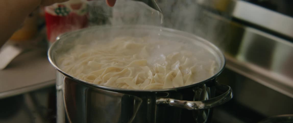 A person stirring pasta in a large pot
