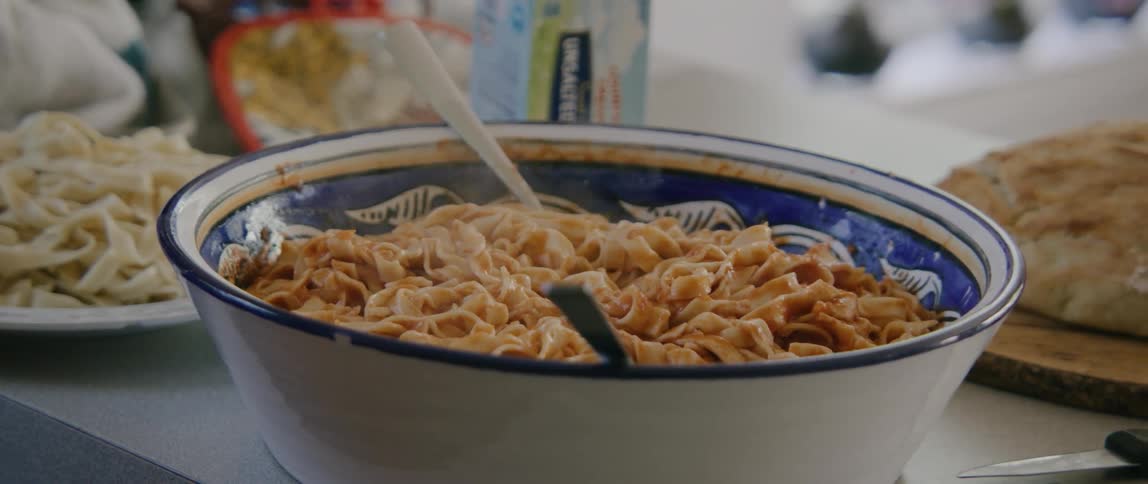 A person stirring a bowl of pasta in a ceramic bowl