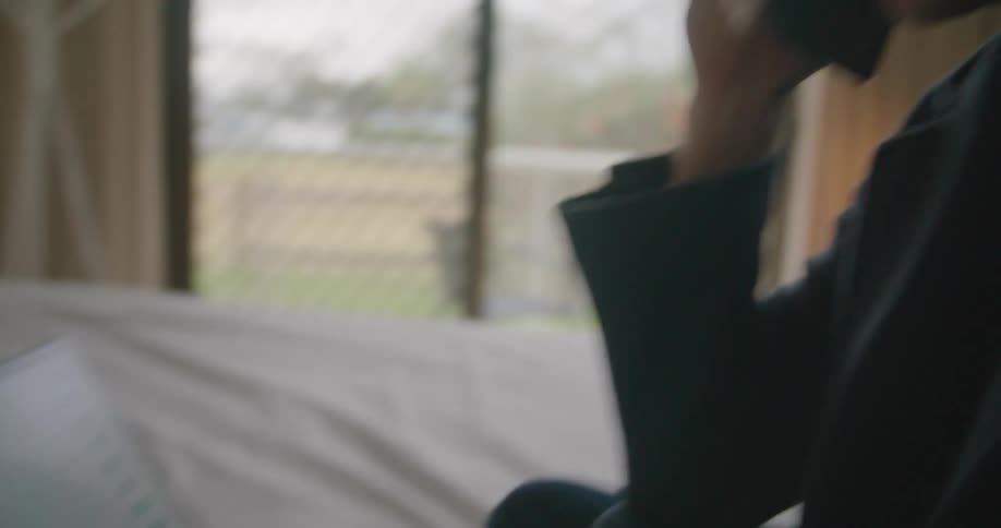 Man sitting in bed talking on the phone working on a laptop
