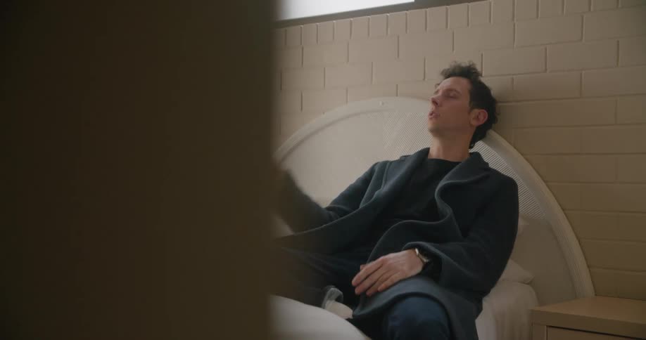 Tired man sitting in bed trying to work on a laptop