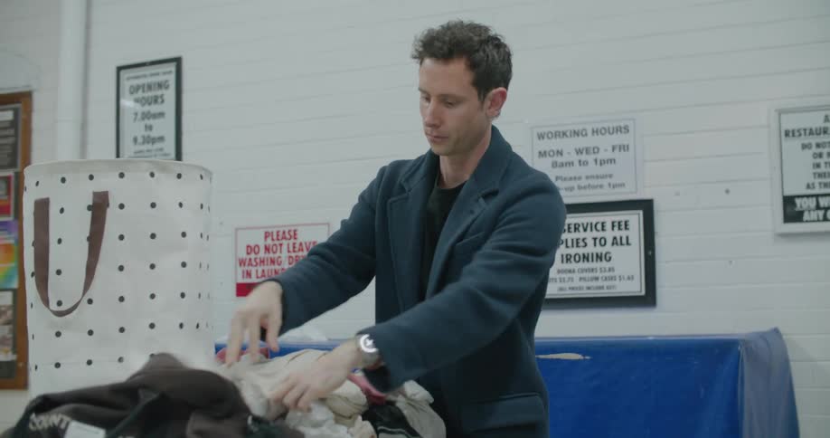 Man folds laundry at a laundromat