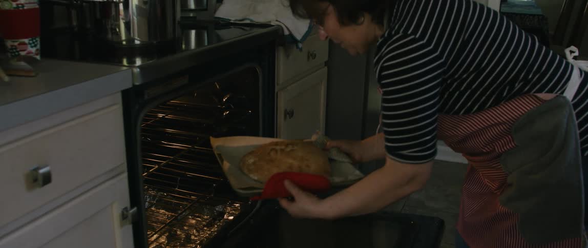 Woman removes a baked food item from the oven and places it on the counter