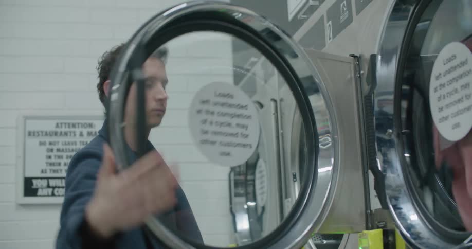 Young man doing laundy in a laundromat