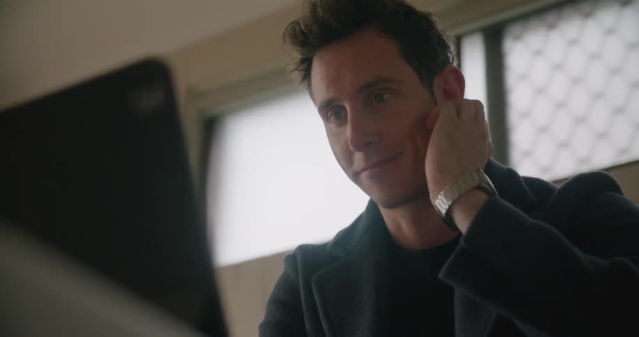 A man sitting inside chatting towards a laptop computer on a video call