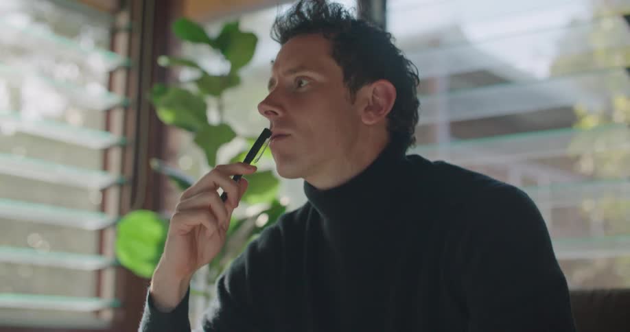 A man in a turtleneck sweater brainstorming ideas and writing them in a notebook