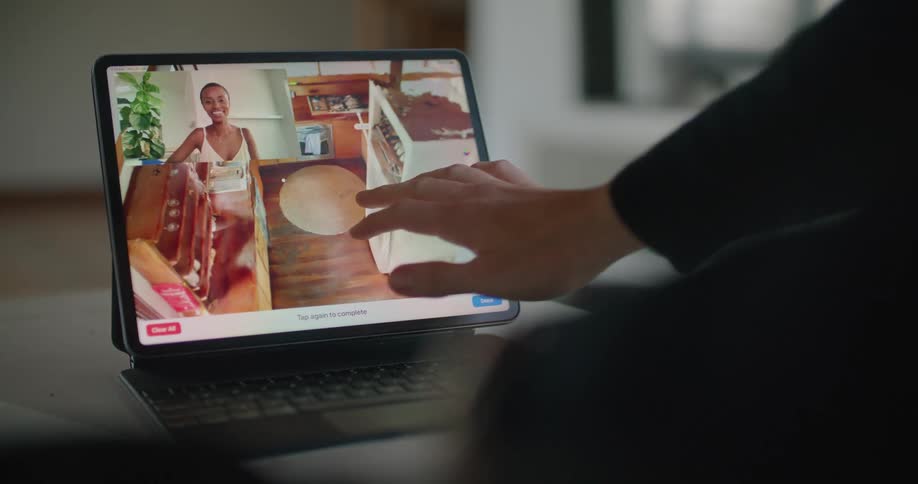 A person in a room using a laptop on a table with a wall in the background