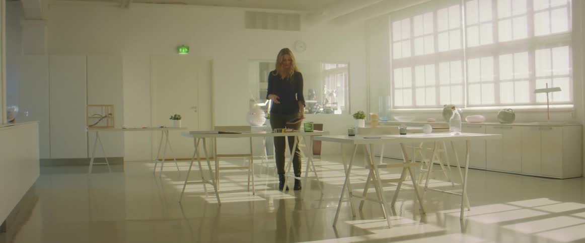 Woman carries a flat object into a room and places it on a desk