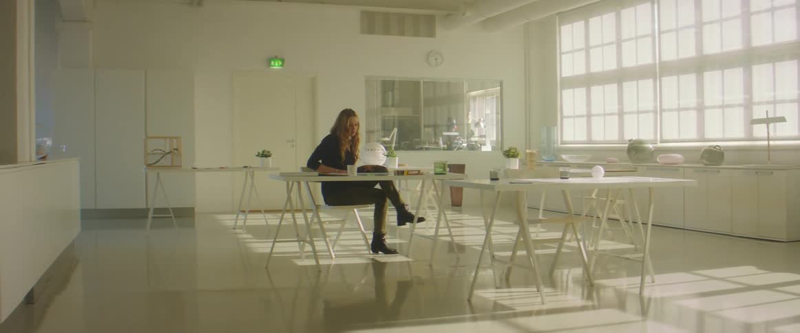 A woman sits down in a chair alone in a room during the day