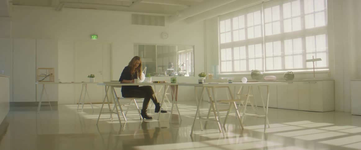 A woman working at a table alone in an office space