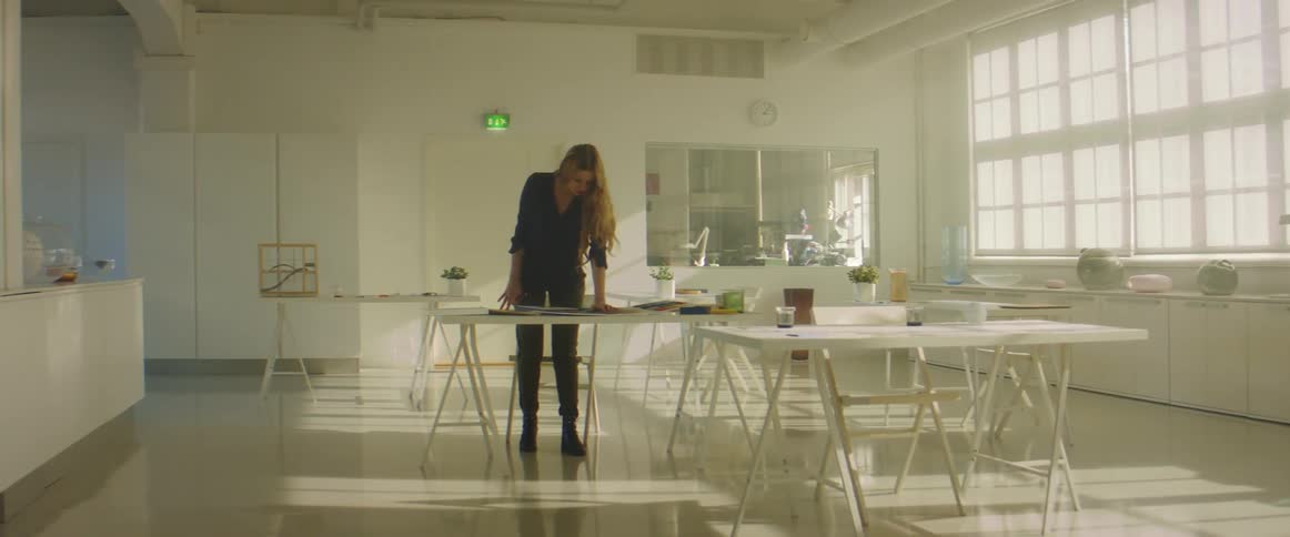A lone woman standing while working over a table in an office