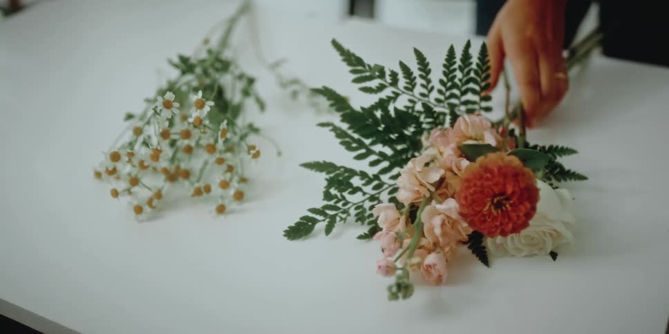 A woman places two bouquets of flowers on a white table