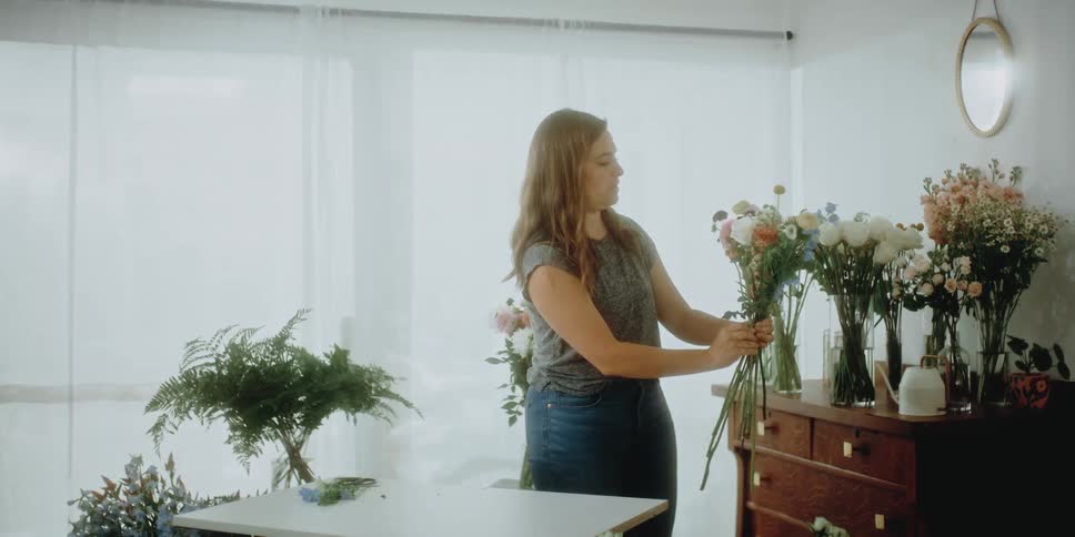 A woman is putting together a flower arrangment
