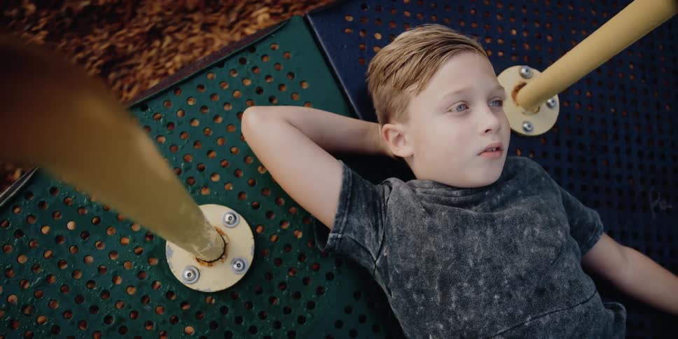 Young boy lays on his back on an amusement park ride as it spins around