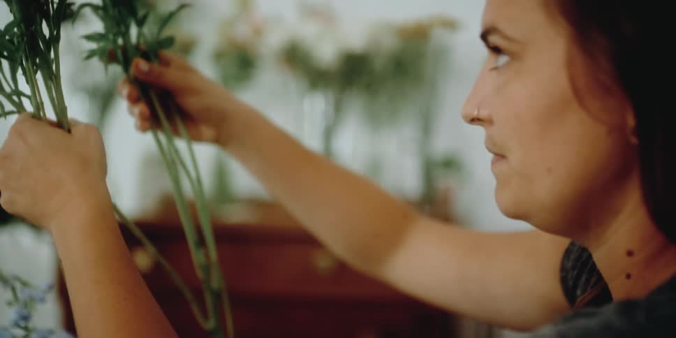 Woman wearing a nose ring removes flowers from a bouquet