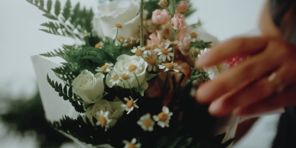 A woman arranges flowers in a bouquet