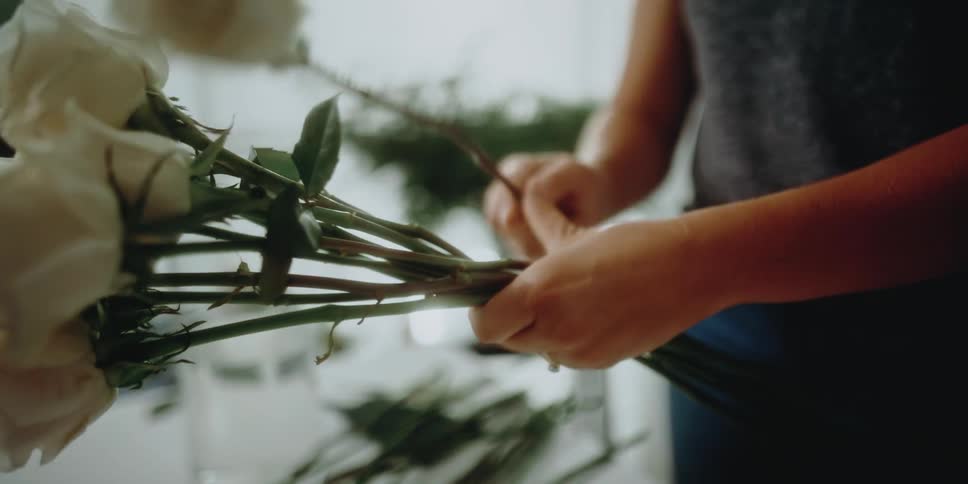 Woman collects long stemmed flowers to form arrangement