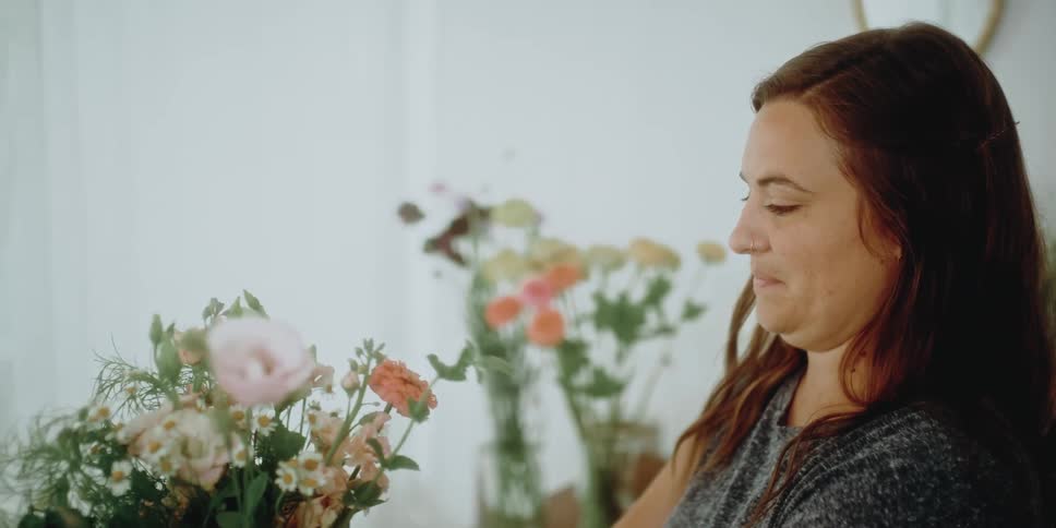 A flower pulls an orange carnation from one flower arrangement to add to another