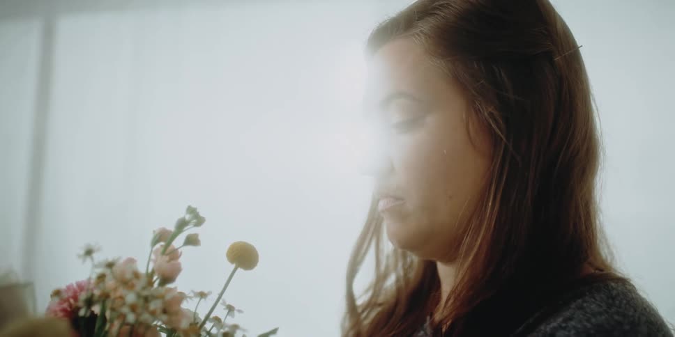 A florist moves pieces around in a near completed flower bouquet