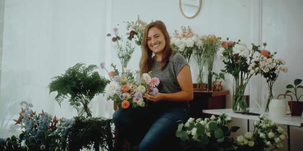 A woman is sitting in a room of flower arrangements